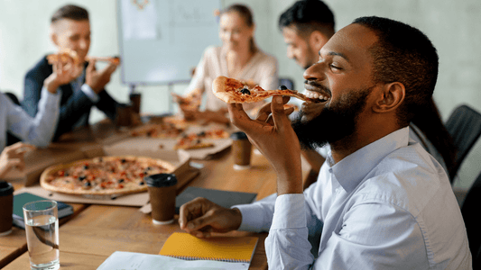 Menschen sitzen an einem Tisch zusammen und essen Pizza