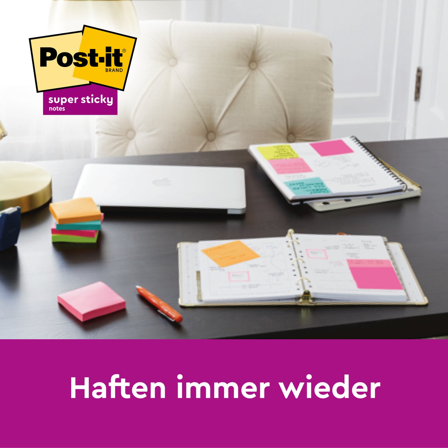 Ein Schreibtisch mit einem geschlossenen Laptop, offenen Planern, Stiften und Stapeln von blauen Post-it® Super Sticky Z-Notes in einem weißen Bärenspender (76 mm x 76 mm, 45 Blatt/Block, 2 Blöcke/Packung) von 3M Deutschland GmbH. Das Post-it-Logo befindet sich oben links; der deutsche Text lautet: "Haften immer wieder.
