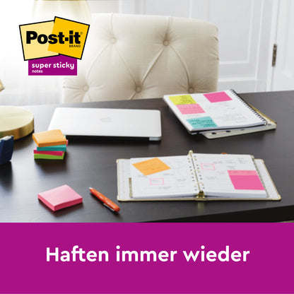 Ein Schreibtisch mit 3M Deutschland GmbH Post-it® Super Sticky Notes (76 mm x 76 mm, 90 Blatt/Block), Notizbüchern, einem geschlossenen Laptop und Stiften. Auf den aufgeschlagenen Notizbüchern sind mehrere Zettel aufgeklebt. Der Text lautet: "Haften immer wieder.