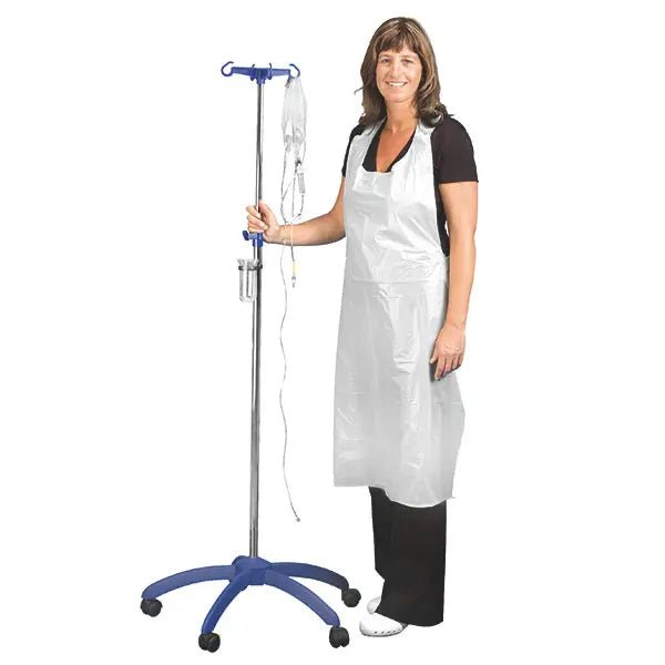 Une femme vêtue de noir sourit en tenant une perche à perfusion. Elle porte les tabliers jetables Altruan Clinhand pour femmes, 120 cm (50 pièces). Le tablier jetable blanc se détache sur le fond sobre.