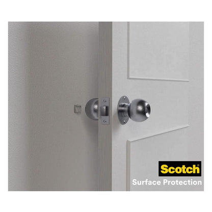 Une porte blanche avec un bouton rond en argent est ouverte et cabosse le mur clair. 3M Deutschland GmbH Scotch® tampons élastiques absorbant les chocs pour murs SP91A64 (auto-adhésifs, transparents, Ø 22 mm) offrent une protection murale efficace; logo visible en bas à droite.