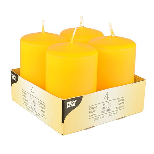 Quatre bougies piliers Starpak « Ivory » (Ø 50 mm, 80 mm, sommet plat) sont disposées dans un support en carton avec l'inscription « Starpak ». L'emballage multilingue met en avant la qualité de la cire et indique clairement que le paquet contient quatre bougies.