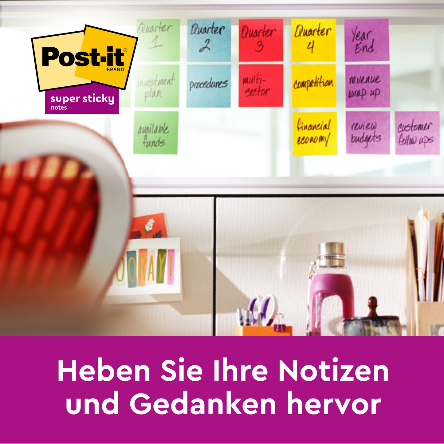 Ein Arbeitsbereich mit 3M Deutschland GmbH Post-it® Super Sticky Notes im Großformat, Pink, Liniert (101mm x 152mm), beschriftet nach Quartalen an einer Glaswand; Stuhl, Bücher und Zubehör in der Nähe. Deutscher Text: "Heben Sie Ihre Notizen und Gedanken hervor.