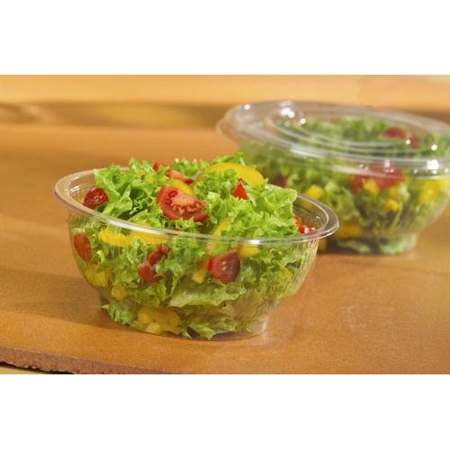 Un couvercle Starpak 50 pour bols à salade, R-PET rond Ø 18 cm, clair, couvre une salade de légumes-feuilles, tomates cerises et poivrons jaunes sur un fond brun. En arrière-plan, un autre contenant à salade Starpak en R-PET clair est visible.