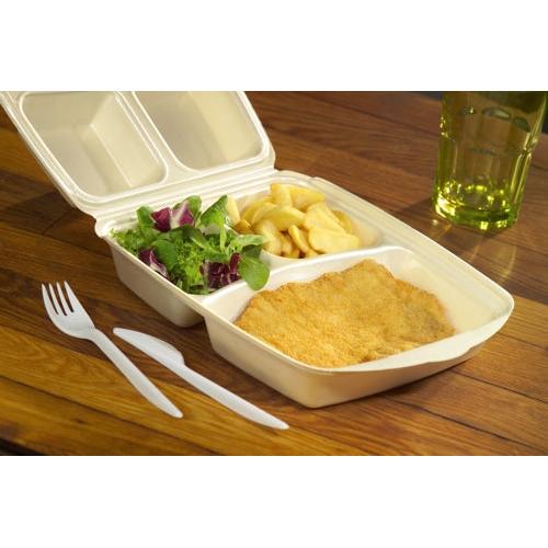 Une boîte à menu Starpak 50 avec couvercle rabattable, XPS beige laminé, contient une escalope panée, des frites et une salade verte. À côté se trouvent une fourchette en plastique et un couteau; en arrière-plan, une boisson jaune-verte dans un verre.
