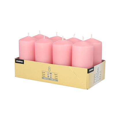Un plateau en carton contient 8 bougies cylindriques roses Starpak (Ø 50 mm · 100 mm), disposées en deux rangées de quatre pièces chacune. L'emballage jaune clair, avec des informations sur le produit à l'avant et à l'arrière, crée une atmosphère chaleureuse.