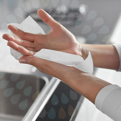 Une personne sèche ses mains au-dessus d'un évier avec des mouchoirs pliants Kleenex® - Blanc/Grand (15 paquets x 124 feuilles | carton) de Kimberly-Clark GmbH, avec les deux mains et une partie de l'évier visibles en arrière-plan.
