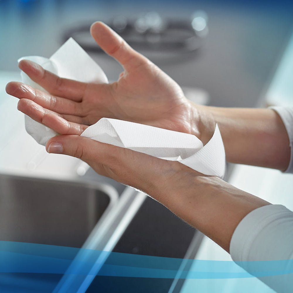 Une personne utilise une serviette en papier blanche Scott® - MultiFold (Kimberly-Clark GmbH, 16 clips x 250 feuilles) au-dessus d'un évier dans une cuisine moderne pour un séchage des mains hygiénique.