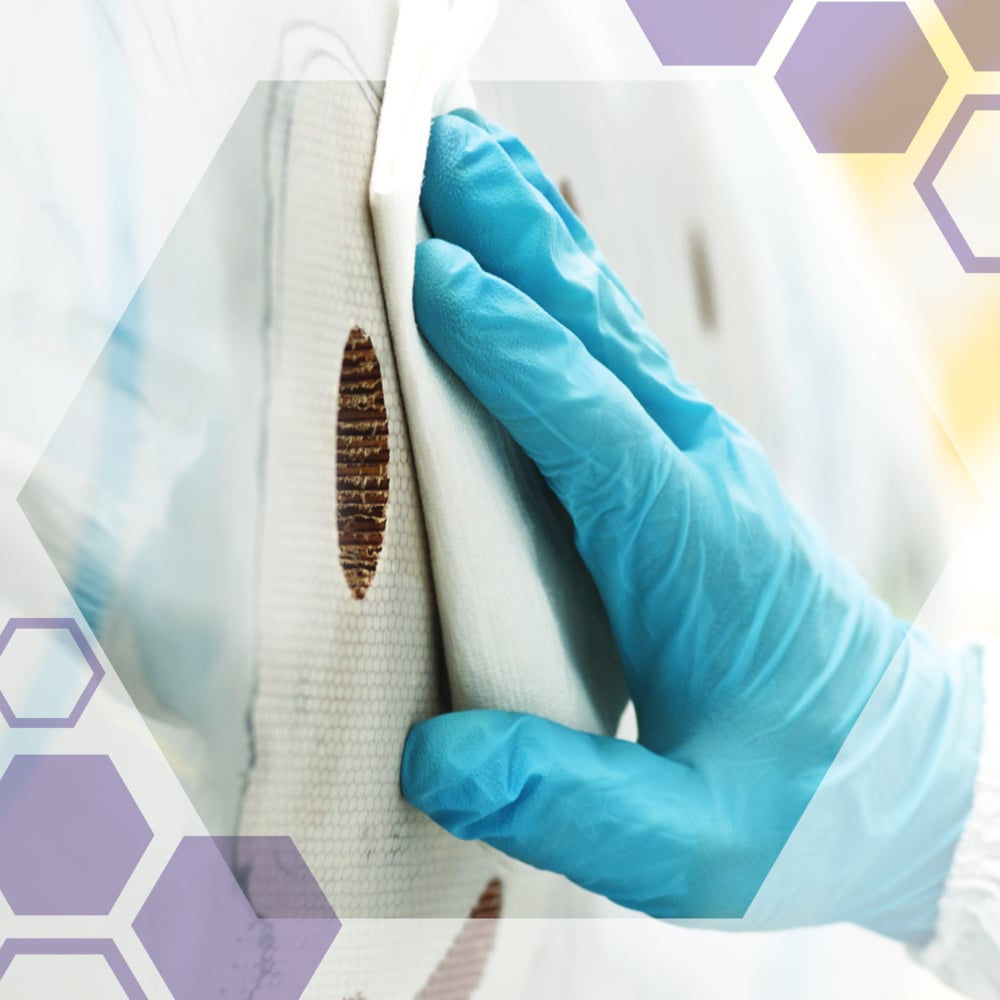 Une main gantée nettoie une surface blanche avec des taches marron à l'aide de lingettes de précision Kimtech® Science (Petite, 30 x 286) de Kimberly-Clark GmbH. Des hexagones semi-transparents mettent en valeur ces lingettes sans peluches, idéales pour le nettoyage en laboratoire.