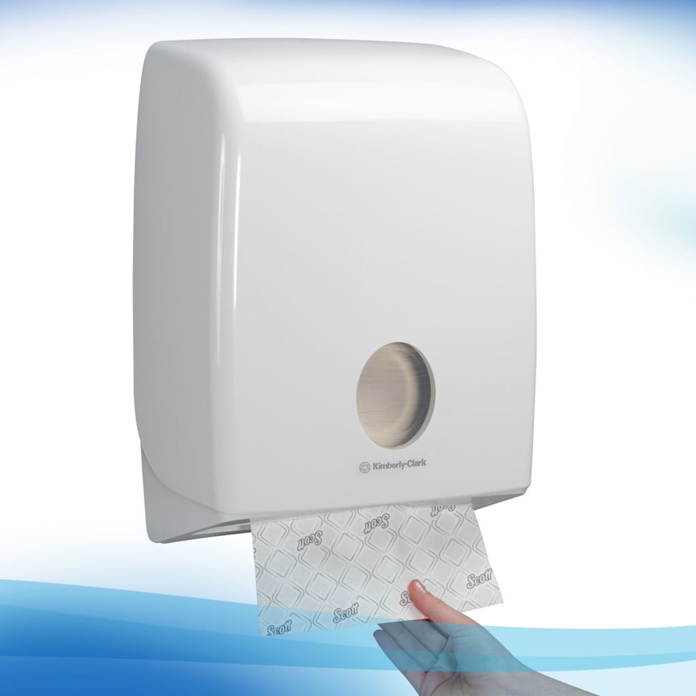 Un distributeur mural blanc de Kimberly-Clark GmbH distribue une feuille unique de serviettes Scott® - Narrow-Fold / Blanc par l'ouverture frontale métallique, assurant ainsi un séchage des mains hygiénique à chaque tirage.