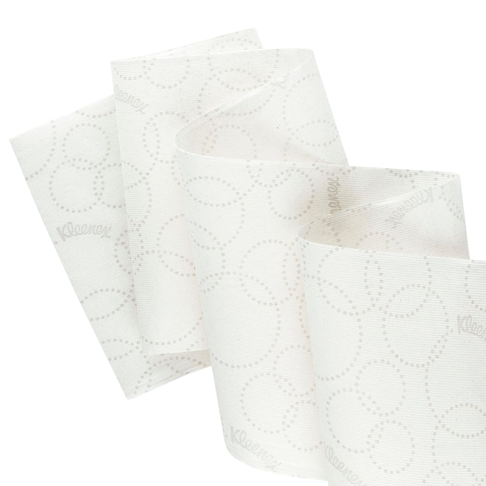 Gros plan d'un rouleau de serviettes blanches Kleenex® Ultra™ Slimroll™ de Kimberly-Clark GmbH avec un motif discret de points et un déroulement partiel, pour montrer son adaptation aux systèmes de distribution étroits; 6 rouleaux par carton.