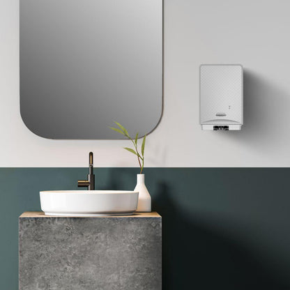 Une salle de bain moderne dispose d'un miroir rond, d'un lavabo blanc, d'un robinet noir et du mousse nettoyante pour les mains Scott® Control™ (4 cartouches) de Kimberly-Clark GmbH pour une hygiène des mains optimale. À côté du lavabo se trouve un vase avec des feuilles vertes, à droite se trouve un chauffe-eau.