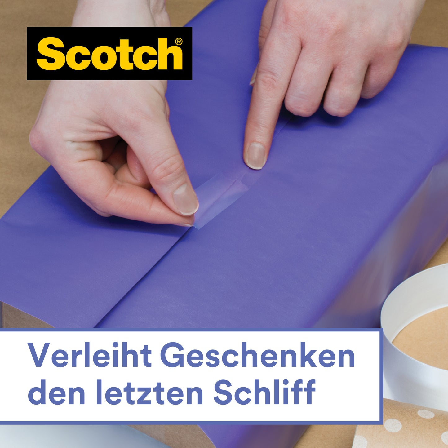 Jemand verschließt lila Geschenkpapier mit Scotch® Geschenk-Satinklebeband (1 Rolle, 19 mm x 25 m) von 3M Deutschland GmbH. Oben links erscheint das Scotch-Logo, darunter steht: "Verleiht Geschenken den letzten Schliff.