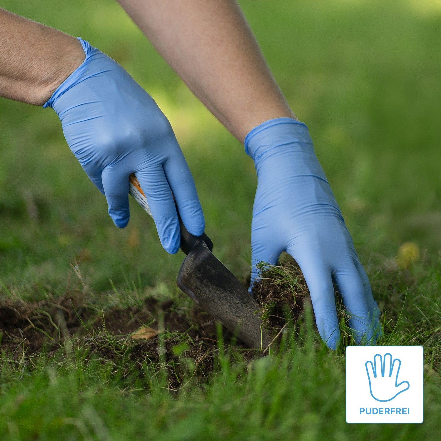 Eine Person, die ARNOMED NITRIL BLUE XTRA STRONG extra dicke Nitril-Einmalhandschuhe der ARNOWA GmbH trägt, benutzt eine Handkelle, um auf einer Wiese Erde umzugraben. In der Ecke ist ein "puderfrei"-Etikett mit einem Handschuhsymbol abgebildet.