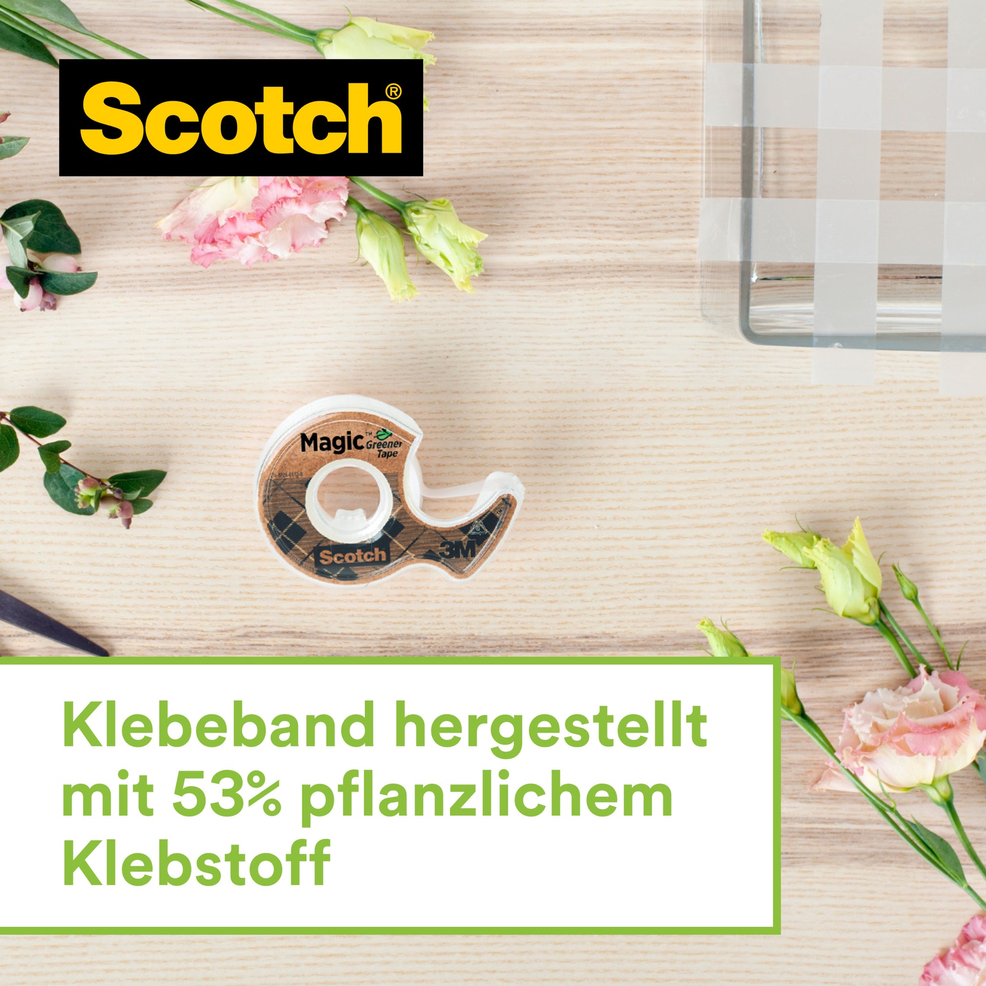 Ein Scotch™ Edelstahl-Klebebandabroller mit zwei Rollen Scotch® Magic™ Klebeband (66% pflanzenbasiert, 19 mm x 13,9 m) von 3M Deutschland GmbH liegt auf hellem Holz neben pink-weißen Blumen.