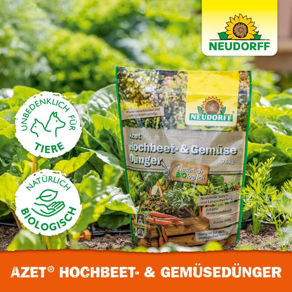 Dans le jardin potager se trouve un sac d'engrais Azet pour potager et légumes de Neudorff Shop, un engrais organique pour légumes et herbes. Les étiquettes indiquent une qualité respectueuse des animaux, naturelle et biologique. Des plantes vertes et de la terre sont visibles.