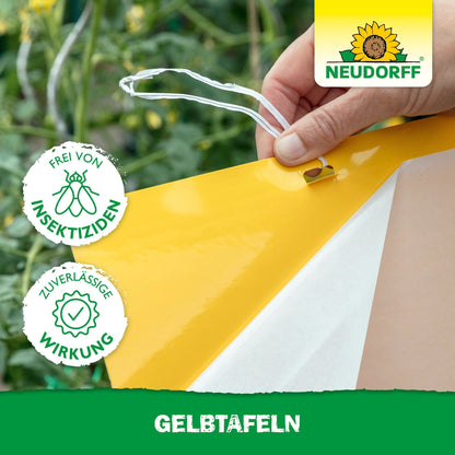 Une main suspend une plaque jaune (grand format) du Neudorff Shop dans un jardin pour se protéger des ravageurs des plantes. L'image montre le logo Neudorff, un sceau pour l'application sans insecticide et efficace et "PLAQUES JAUNES" en bas.