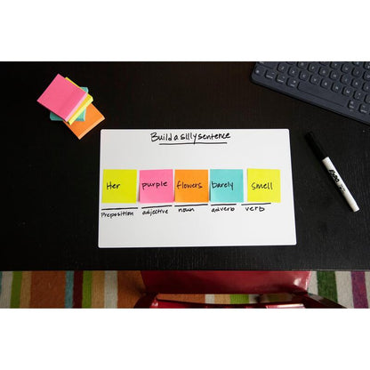 Sur un bureau noir se trouve un tableau blanc avec l'inscription "Construire une phrase amusante". Les cubes de notes Post-it® Ultra-Couleurs de 3M Deutschland GmbH, 76x76 mm, montrent les catégories de mots. Également sur le bureau : un marqueur effaçable à sec, un bloc-notes et un clavier.