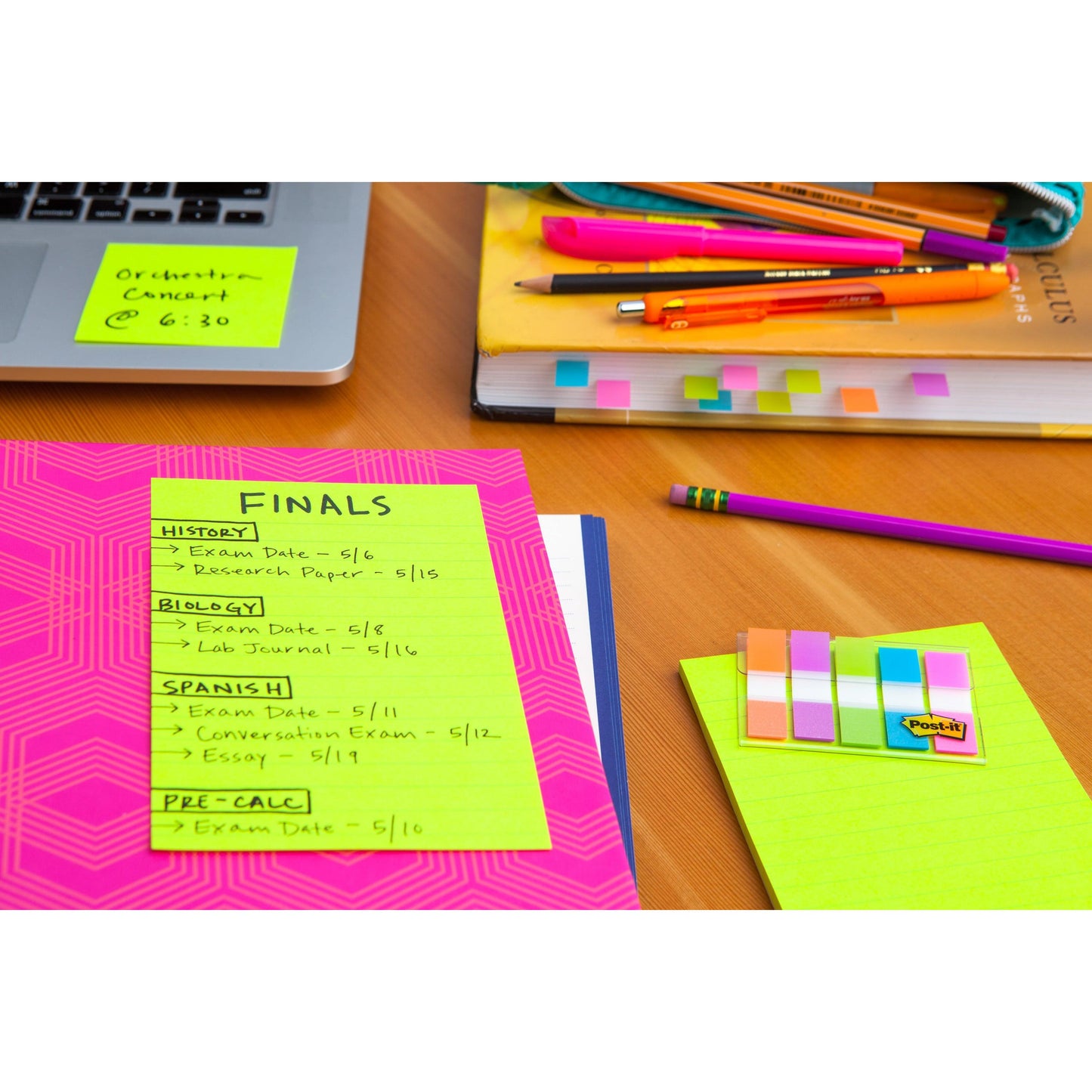 Auf dem Schreibtisch liegen bunte Schulsachen, Bücher, Stifte und eine Mappe mit einem 3M Post-it® Super Sticky Note (liniertes Großformat, 101x152mm), auf dem der Stundenplan für die Abschlussprüfungen in Geschichte, Biologie, Spanisch und Vorkalkulation steht.