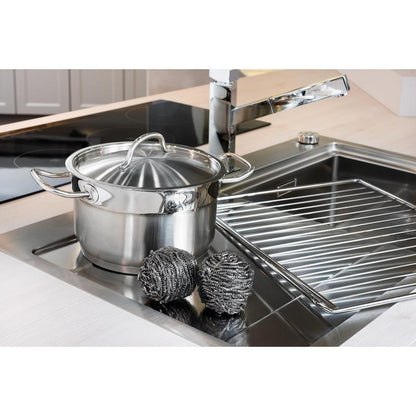 Une casserole en acier inoxydable avec couvercle est placée dans l'évier à côté de deux spirales en acier inoxydable Scotch-Brite® (3M Deutschland GmbH, 3 pièces par paquet) et d'un égouttoir - pour un nettoyage facile de la cuisine même en cas de salissures tenaces.