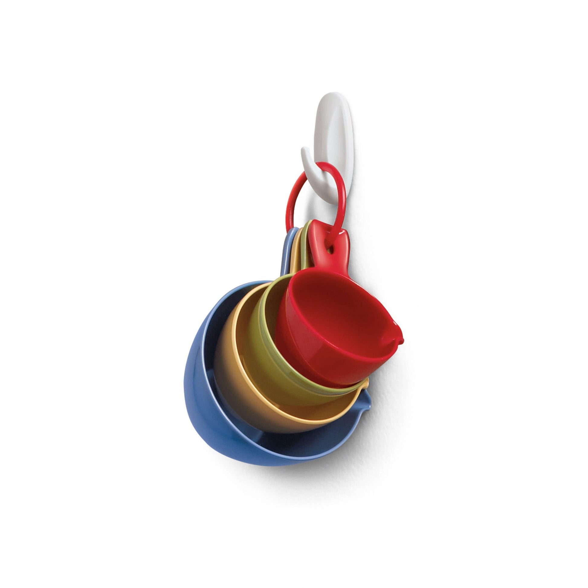 An einem Command™ Small Designer-Haken, 17082 von 3M Deutschland GmbH hängt an einer weißen Wand ein Set aus bunten Plastikmessbechern und -löffeln, die ineinander gesteckt und mit einem roten Ring befestigt sind.