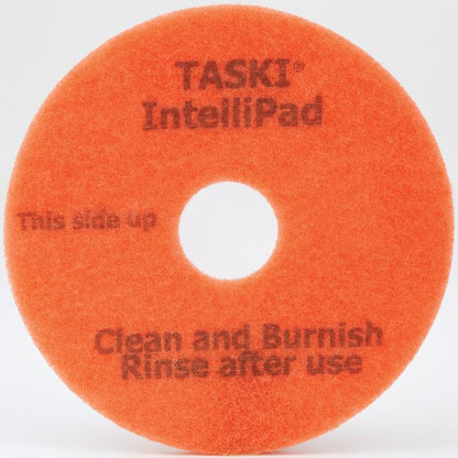Le TASKI Intellipad, un tampon de nettoyage et de polissage combiné pour l'entretien de Diversey Deutschland GmbH & Co. OHG, est orange, rond, avec un trou central et l'inscription "This side up" - idéal pour un nettoyage polyvalent des sols.