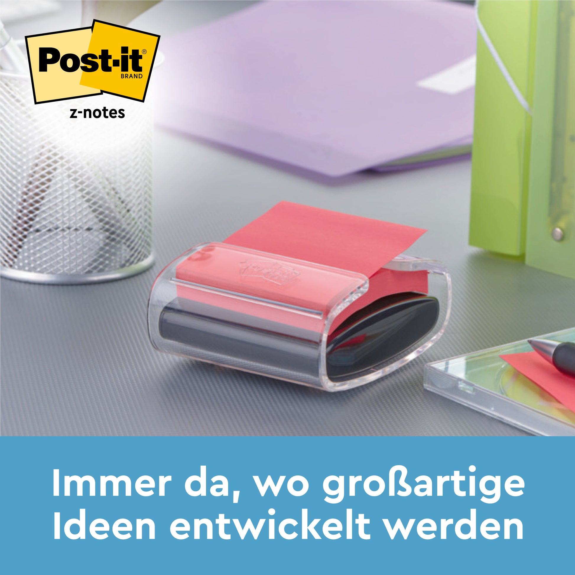 Ein schwarzer Post-it® Z-Notes Dispenser PRO mit gelben Super Sticky Z-Notes (76x76 mm, 90 Blatt) von 3M Deutschland GmbH steht auf einem Schreibtisch neben einem Stifthalter, einem grünen Ordner und einem Notizbuch. Text: "Immer da, wo großartige Ideen entwickelt werden.