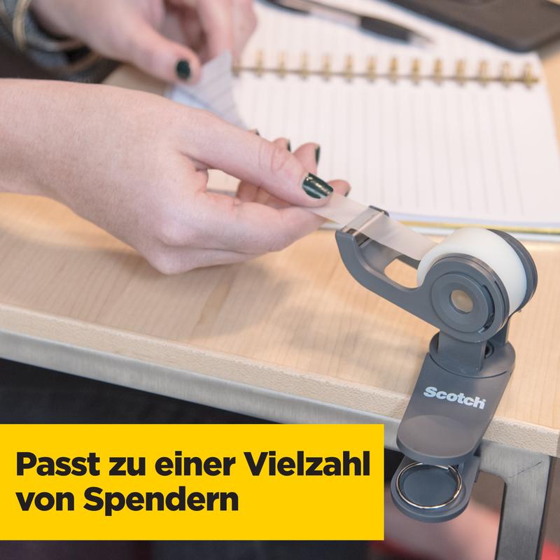 Une personne tire le ruban adhésif invisible Scotch® Magic™ (3M Deutschland GmbH, pack avantage de 8 rouleaux, 19 mm x 33 m) d'un distributeur sur un bureau, où il est écrit en bas en lettres jaunes "S'adapte à une variété de distributeurs".