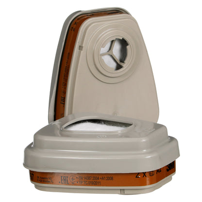 Abgebildet sind zwei rechteckige beige-braune 3M™ Filtersatz 6002-1 A2P2 Filterpatronen der 3M Deutschland GmbH, eine aufrecht und eine flach. Jede hat eine zentrale runde Öffnung und aufgedruckte Informationen. Geeignet zum Schutz gegen organische Dämpfe.