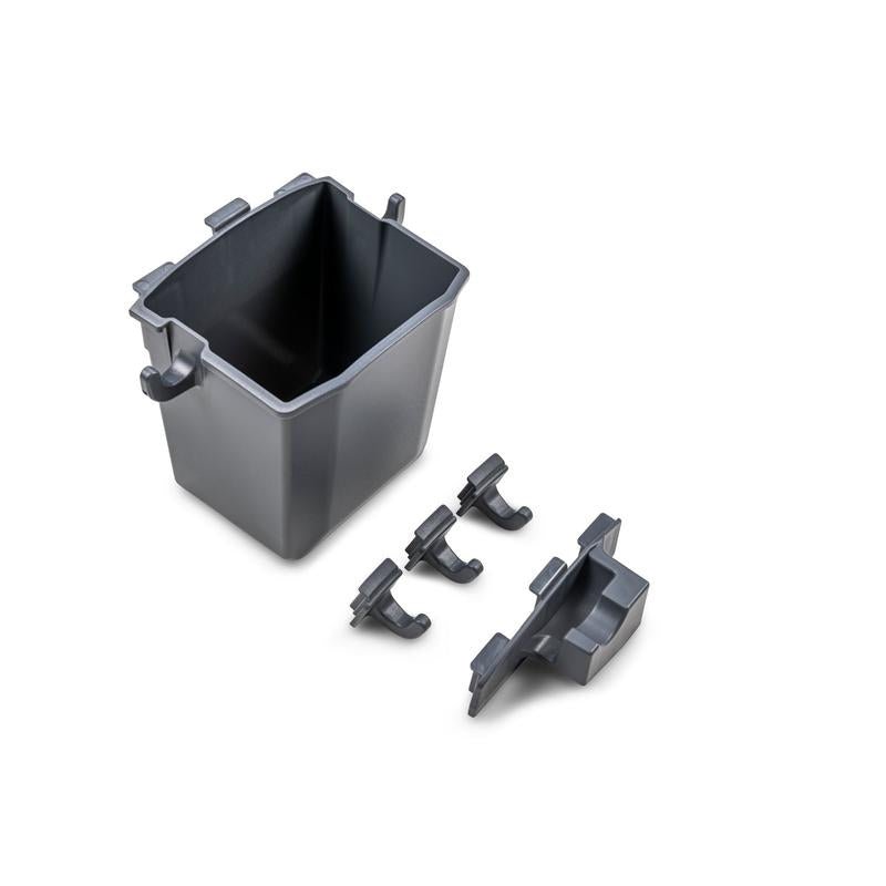 Un seau d'accessoires gris pour Ultimaxx de Diversey Deutschland GmbH & Co. OHG avec quatre clips noirs et un accessoire rectangulaire est ouvert et vide sur un fond blanc - parfait pour une utilisation avec votre support d'accessoires (1 pièce).