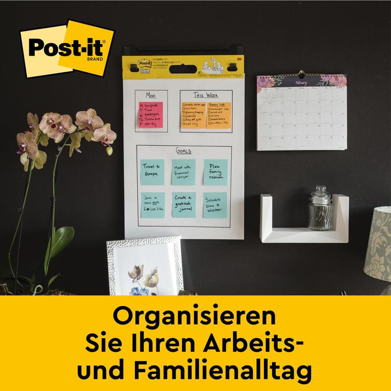 Un mur de bureau avec le tableau de réunion auto-adhésif Post-it® Super Sticky/flipchart 559 de 3M Deutschland GmbH (63,5 x 76,2 cm), calendrier mensuel, étagère avec verre, orchidée et photos. Texte : "Organisez votre quotidien.
