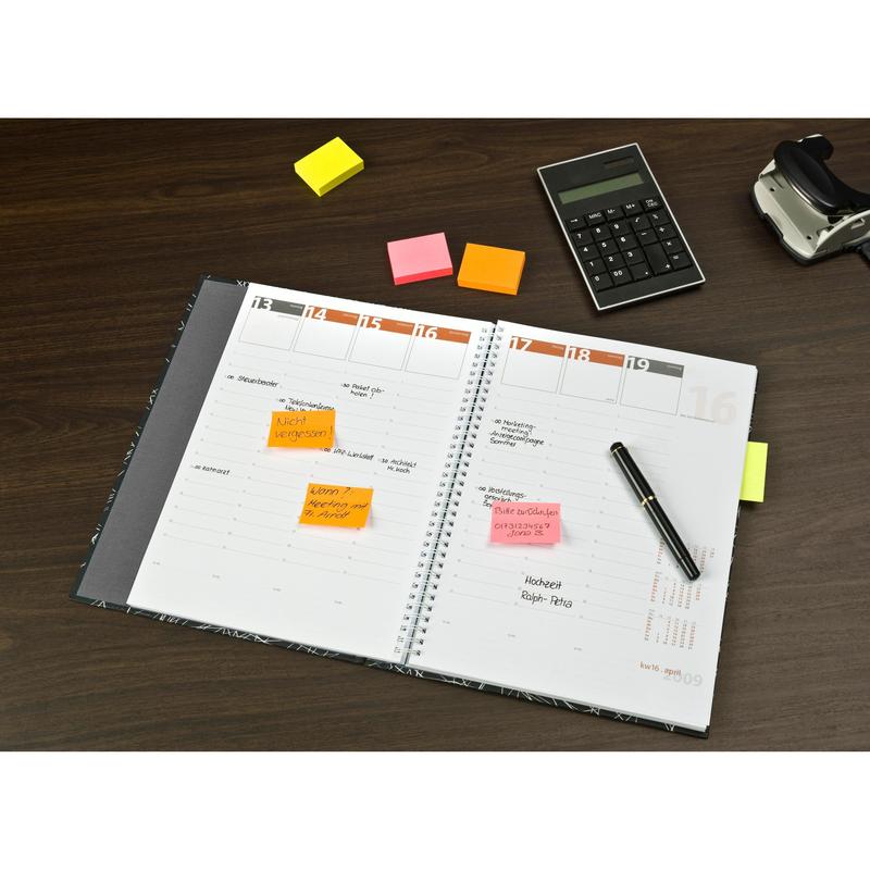Un agenda ouvert avec des notes manuscrites et des notes Post-it® colorées en différentes couleurs néon (38 mm x 51 mm, 100 feuilles/bloc, 3 blocs/paquet, 100% PEFC) de 3M Deutschland GmbH sur une table en bois avec un stylo, une calculatrice et un dévidoir de ruban adhésif.