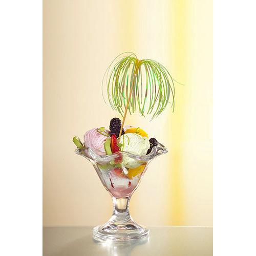 Un bol à dessert en verre avec de la glace, divers fruits et baies est garni d'un pique de décoration PAPSTAR 100 de PAPSTAR GmbH et se tient devant un fond doucement éclairé en jaune – parfait pour des présentations élégantes.