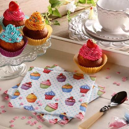 Une table est dressée avec des cupcakes sur un présentoir en verre, une assiette, une cuillère, une tasse à thé blanche et une soucoupe, des vermicelles en forme de cœur rose et des serviettes colorées PAPSTAR 20 serviettes 33x33cm 3-plis 1/4-pli Design Set 5 de PAPSTAR GmbH.