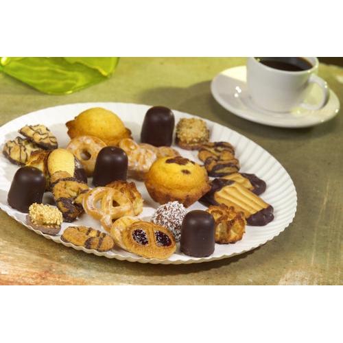 Un PAPSTAR assiette ronde Ø 32 cm, blanche, en carton "pure" de PAPSTAR GmbH avec des biscuits et des pralines se trouve à côté d'une tasse à café blanche sur une table. En arrière-plan, on voit une serviette verte.