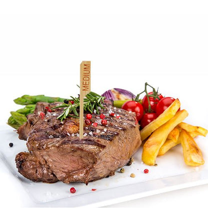 Un steak grillé avec la désignation « medium » et le PAPSTAR 250 marqueur de steak de 9 cm de la PAPSTAR GmbH est servi sur une assiette blanche avec des frites, des asperges, des tomates cerises, des oignons rouges et des herbes - parfait pour la cuisine professionnelle de restaurant.