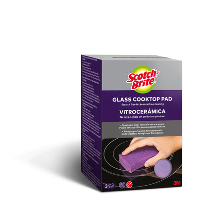 Une boîte de 3 éponges de nettoyage Scotch-Brite™ pour céramique vitrocéramique (3 pièces) montre une main nettoyant une surface de cuisson en verre avec le tampon violet. L'emballage indique qu'il est sans rayures et sans produits chimiques, idéal pour les surfaces en céramique vitrocéramique.