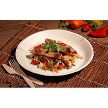 Des brochettes de poulet grillé avec une poêlée de légumes colorés sont servies sur une assiette ronde en palmier "pure" de PAPSTAR GmbH - vaisselle écologique, présentée avec style sur un support tissé avec des couverts en bois et des poivrons frais en vue.