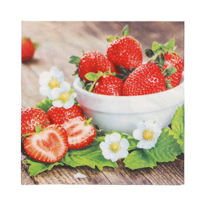 Un bol blanc avec des fraises repose sur du bois, entouré de baies, de feuilles vertes, de fleurs de fraise et de serviettes PAPSTAR 20, 33 cm x 33 cm, 3 plis, 1/4 pliage, Design Set 2 de PAPSTAR GmbH, soigneusement pliées.