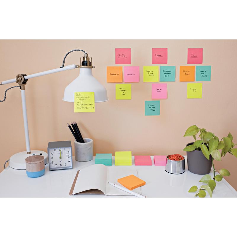 Sur le bureau bien rangé se trouvent une lampe, une horloge, une plante, des fournitures de bureau et un carnet ouvert. Au-dessus, des Post-it® Super Sticky Notes colorés (76 mm x 127 mm, 90 feuilles/bloc) de 3M Deutschland GmbH montrent des tâches et des rappels manuscrits sur le mur.