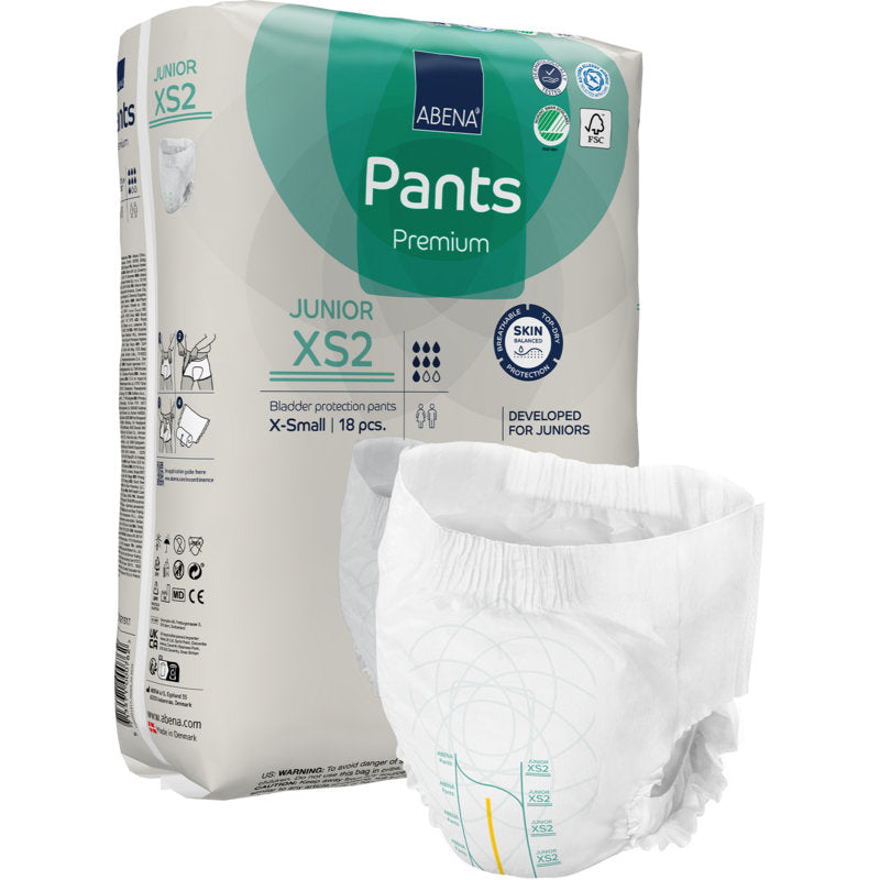 Abgebildet ist eine ABENA Pants Junior Premium, Gr. XS2 Packung (18 Paar) der Abena Re-Seller GmbH mit einer aufgeklappten Hose vorne. Die beigefarbene Verpackung ist mit grünen und blauen Akzenten sowie Produktangaben und Symbolen versehen.