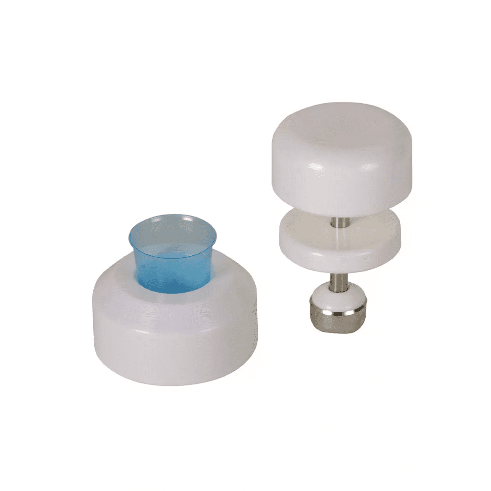 Sur un fond blanc, on peut voir deux ustensiles de cuisine en plastique blanc. L'outil à gauche a une forme cylindrique avec un insert en plastique bleu, tandis que l'outil à droite est un pilon à comprimés AMPri pour gobelets médicaux de la société AMPri Handelsgesellschaft mbH, composé de deux disques blancs reliés par une tige en acier inoxydable avec une base en métal.