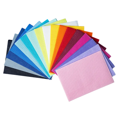 Une sélection de serviettes patients jetables AMPri Dental colorées dans différentes couleurs comme le bleu, le vert, le jaune, l'orange, le rouge, le violet et le rose de la marque AMPri Handelsgesellschaft mbH. Les serviettes sont élégamment disposées en éventail sur un fond blanc.