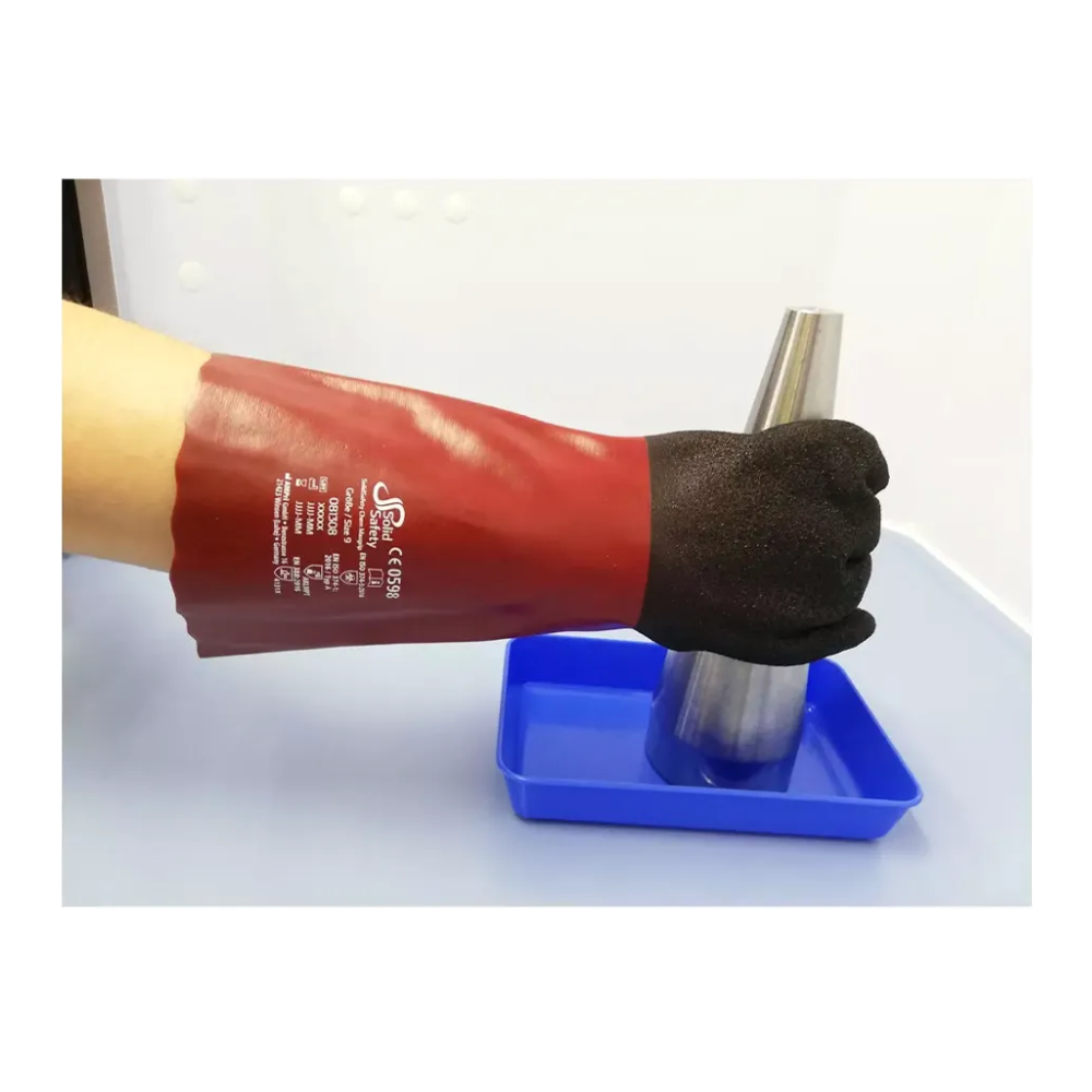 Une personne porte un gant AMPri SolidSafety Chem MaxGrip rouge avec des doigts noirs et des marquages blancs et tient un cône métallique au-dessus d'un plateau bleu. Le gant, connu pour sa protection contre les acides et sa résistance à l'abrasion, se démarque sur un fond simple et clair.