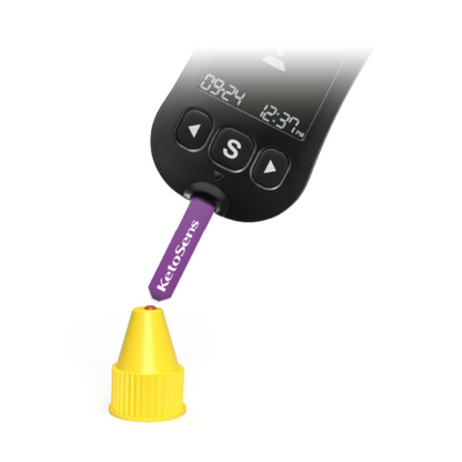 Un appareil de mesure numérique avec un affichage «09:24» et «12:37» est utilisé pour tester une bande violette portant l'inscription «Alphacheck KetoSens β-solution de contrôle de cétone L+M | Emballage (2 flacons)». La bande Alkacheck Alphacheck KetoSens β-solution de contrôle de cétone L+M | Emballage (2 flacons) pointe vers un petit bouchon jaune. L'appareil dispose d'un grand bouton «S» sous l'affichage.