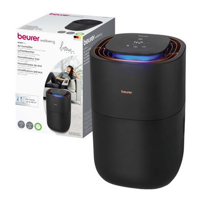 Sur l'emballage, un humidificateur d'air noir Beurer LB 300 de Beurer GmbH avec un panneau de commande numérique sur le dessus est illustré. L'emballage montre une marque et l'image d'une femme se relaxant, indiquant que le produit est destiné à un usage domestique. Le texte multilingue souligne les avantages du produit pour un air intérieur hygiénique.