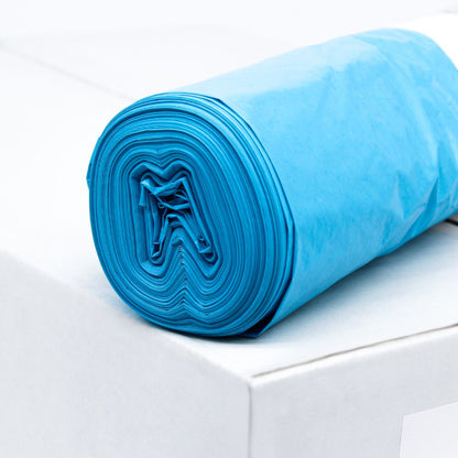 Un rouleau de sacs-poubelle bleus DEISS LDPE Type 60, 20772, 70 litres de EMIL DEISS KG (GmbH + Co.) repose sur une boîte blanche. Ces sacs durables, connus pour leur résistance à la déchirure, sont soigneusement enroulés pour rendre visible la structure en couches du matériau recyclé. L'arrière-plan reste simple et minimaliste.