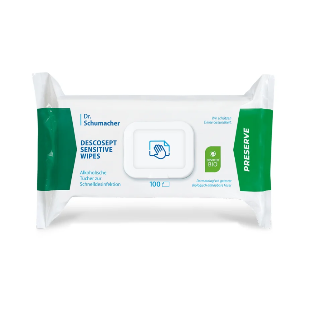 Das Bild zeigt eine Packung Dr. Schumacher Descosept Sensitive Wipes BIO von Dr. Schumacher GmbH, die überwiegend in Weiß gehalten ist und auf beiden Seiten grüne Akzente aufweist. Sie enthält 100 alkoholische Tücher zur materialschonenden Desinfektion. Der Text ist auf Deutsch und enthält ein „Konservieren“-Etikett und ein „Dermatologisch getestet“-Symbol.