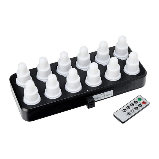 Une station de recharge noire accueille douze lampes blanches en forme d'oignon issues du kit LED de Duni GmbH, « Blanc chaud & Multicolore » – 12 lampes à changement de couleur. À côté se trouve une télécommande rectangulaire permettant de contrôler facilement la couleur et le mode.