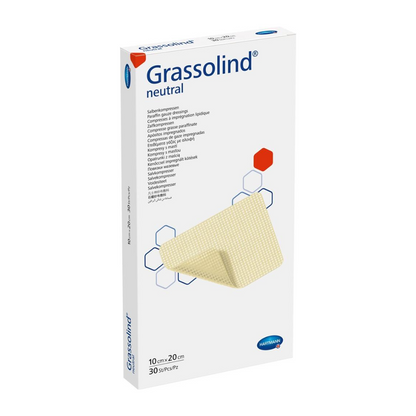 Une boîte de compresse de pommade Hartmann Grassolind®, de différentes tailles, un pansement médical, avec des informations importantes sur le produit et une image de la compresse de pommade sur le devant. L'emballage est principalement blanc.